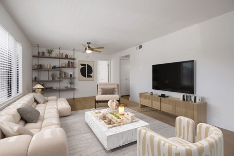 A living room with a white sofa, a coffee table, and a television.