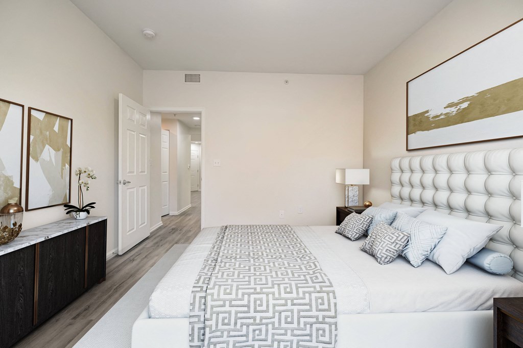 a white bedroom with a large bed and a mirror