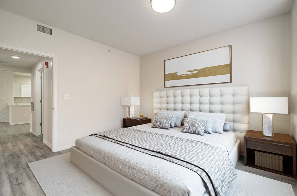a white bedroom with a large bed and a white rug