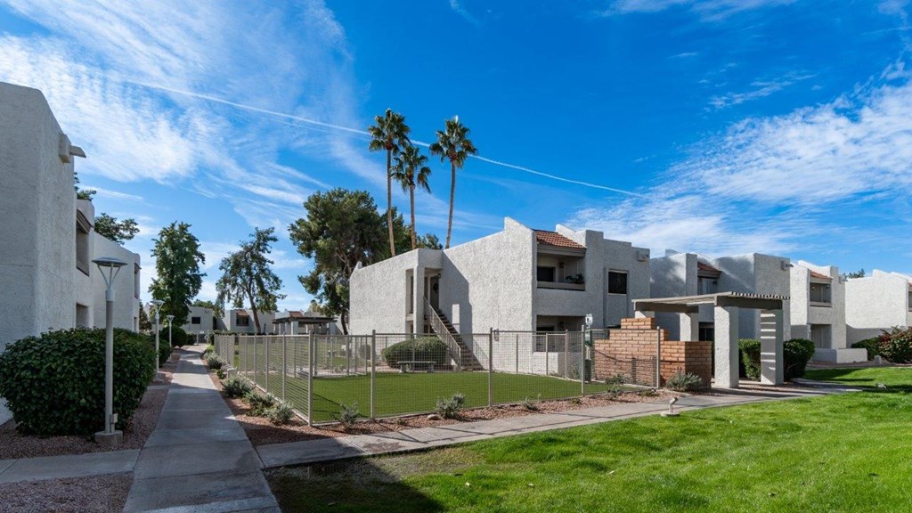 A row of houses with a sidewalk and green grass.