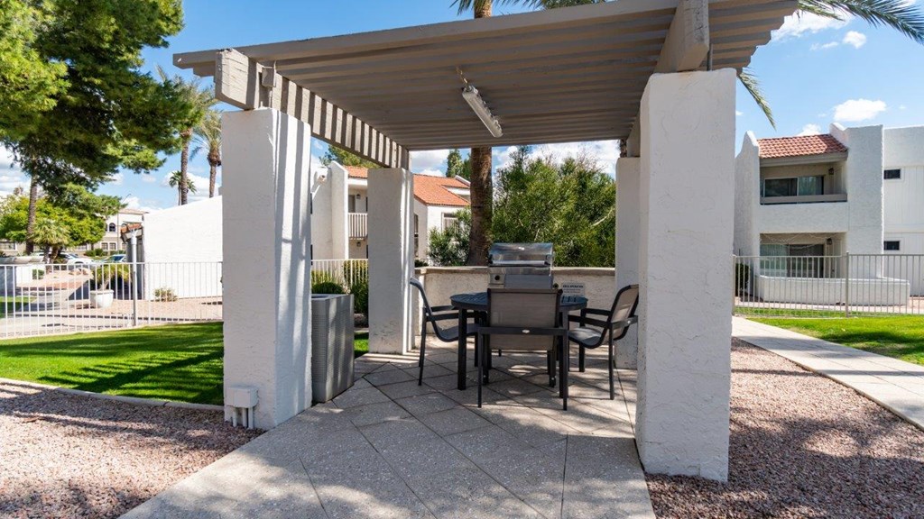 A patio with a table and chairs under a roof.