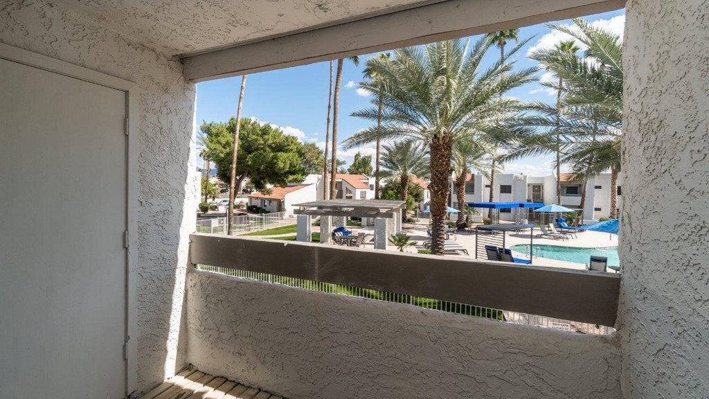 A view from a window looking out at a pool and palm trees.