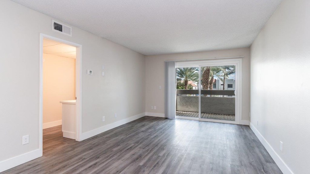 A room with a sliding glass door leading to a balcony.