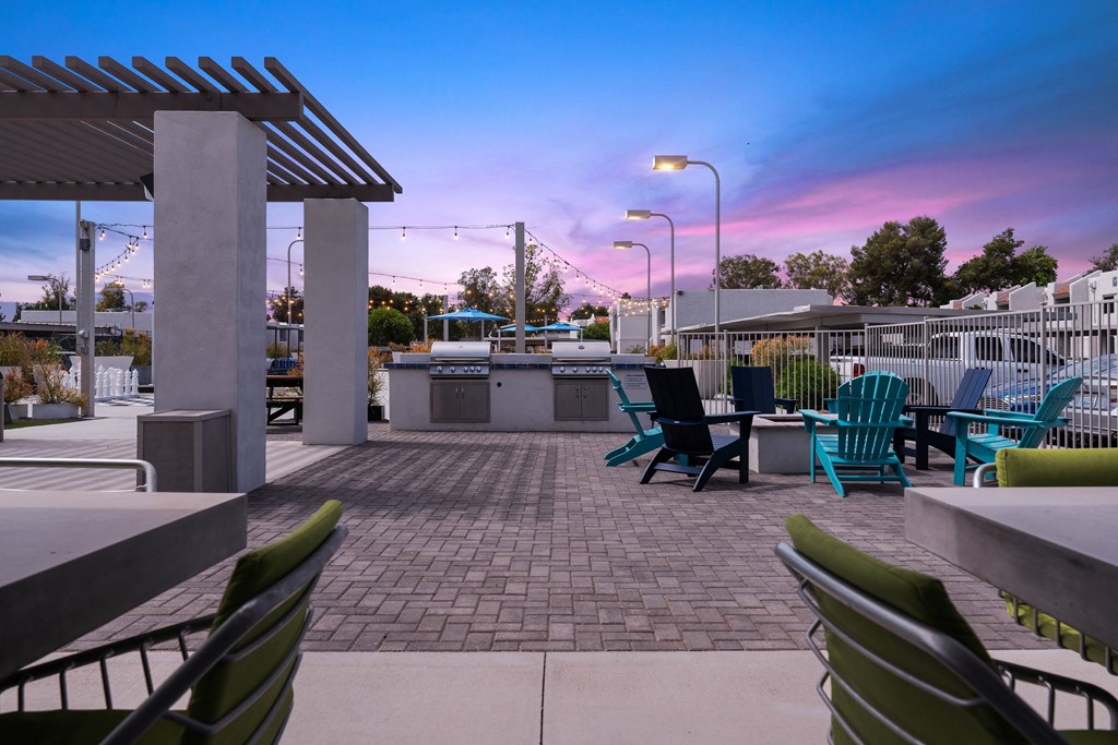 a patio with chairs and a grill at dusk