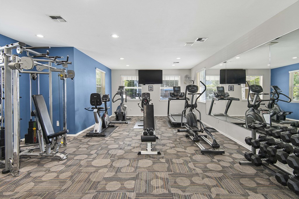 a gym with weights and cardio equipment in a building with blue walls