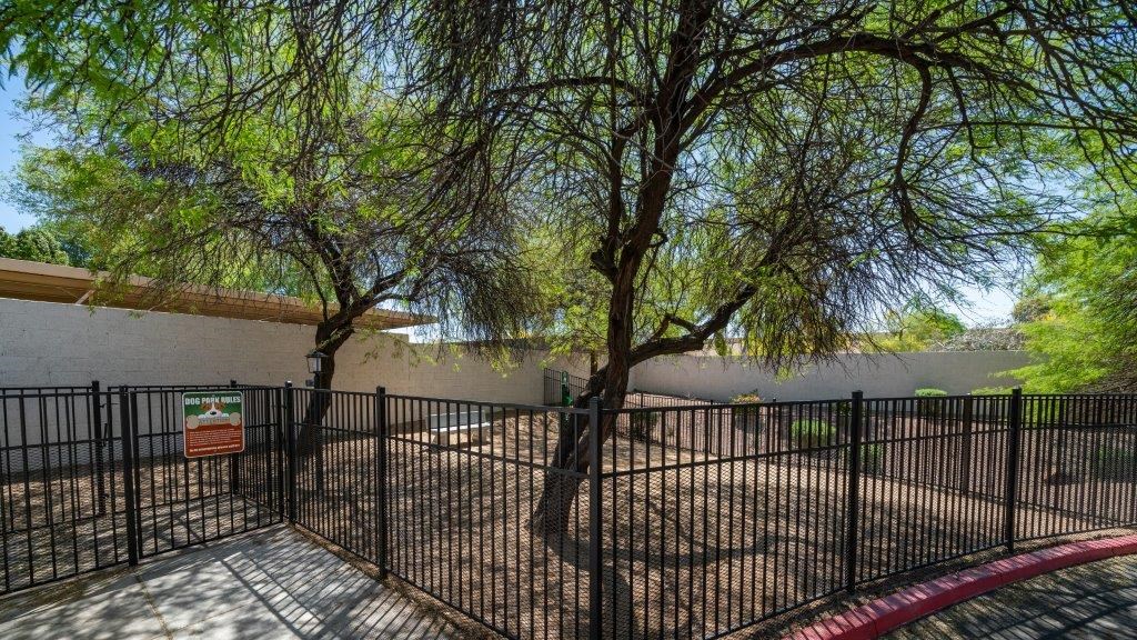 a fenced in area with trees in front of a building