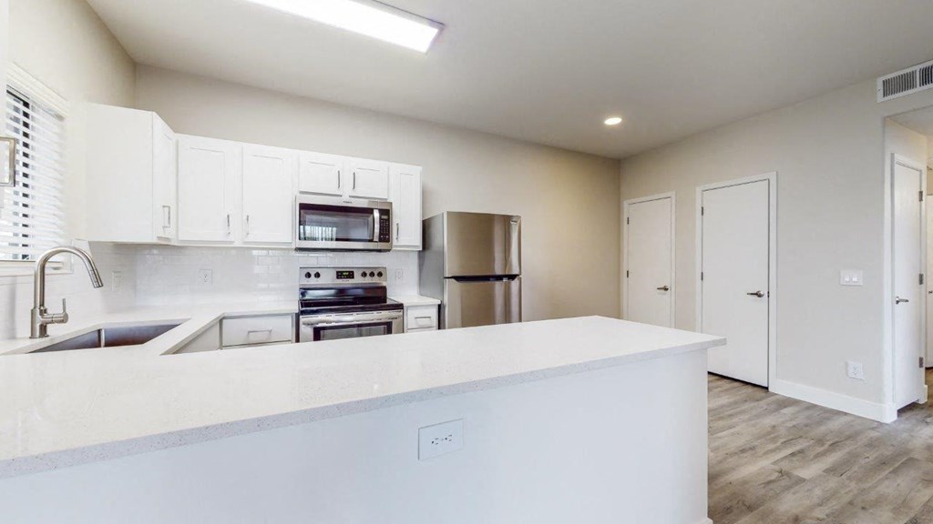 a white kitchen with a counter top and a refrigerator