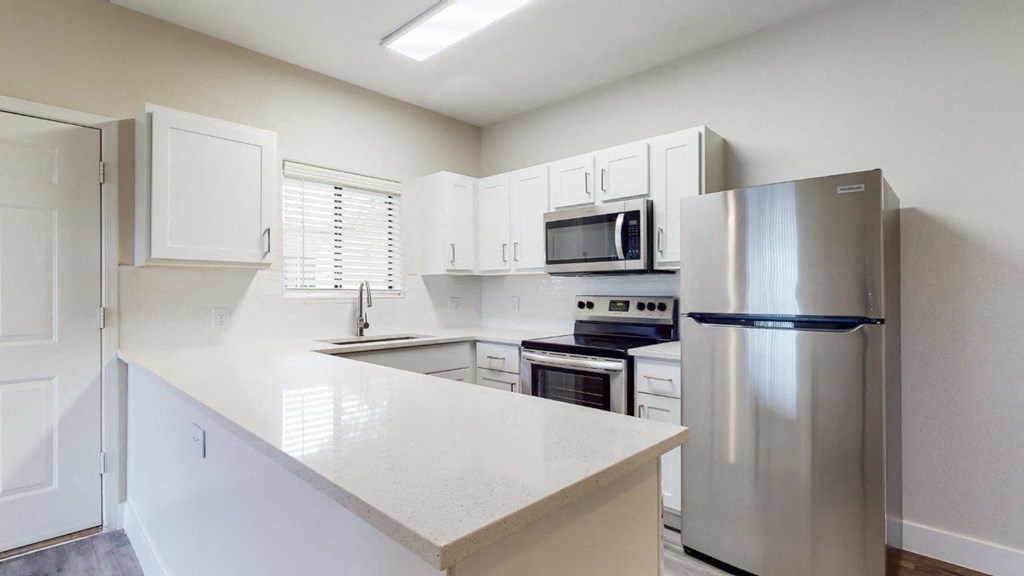 a white kitchen with stainless steel appliances and a counter top