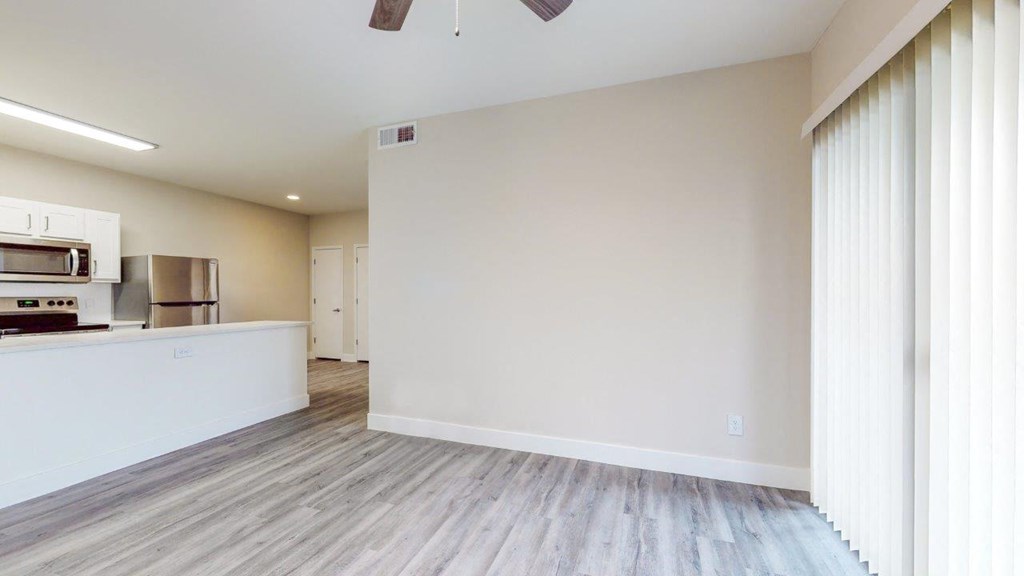 a living room and kitchen with wood floors and white walls