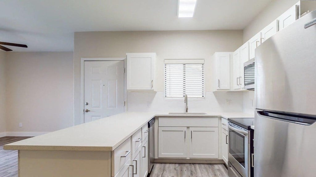an empty kitchen with white cabinets and a refrigerator