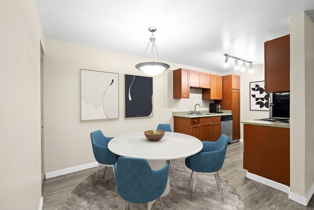 a dining area with a table and chairs and a kitchen in the background
