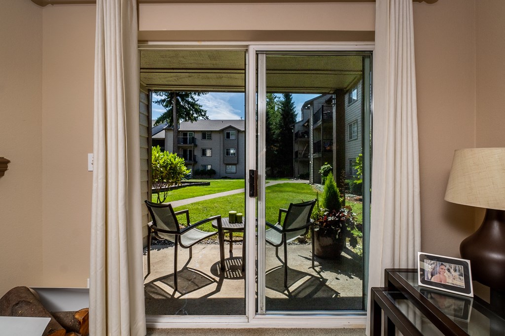 a patio with a table and chairs is seen through a sliding glass door
