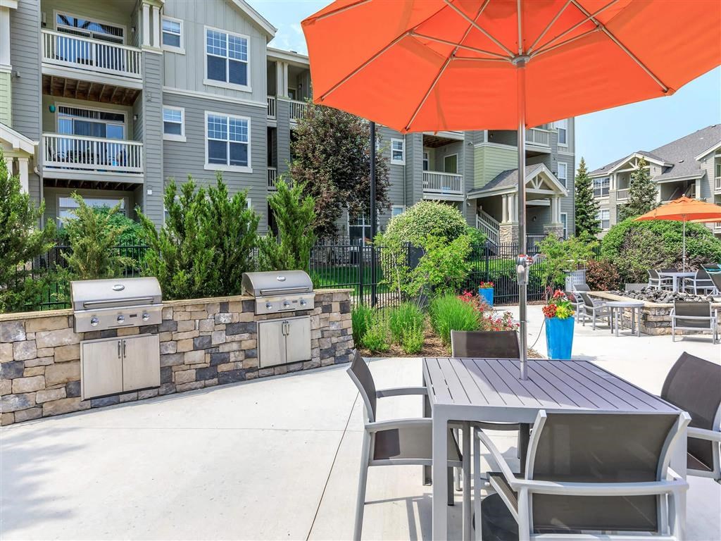 a patio with a table and chairs under an orange umbrella