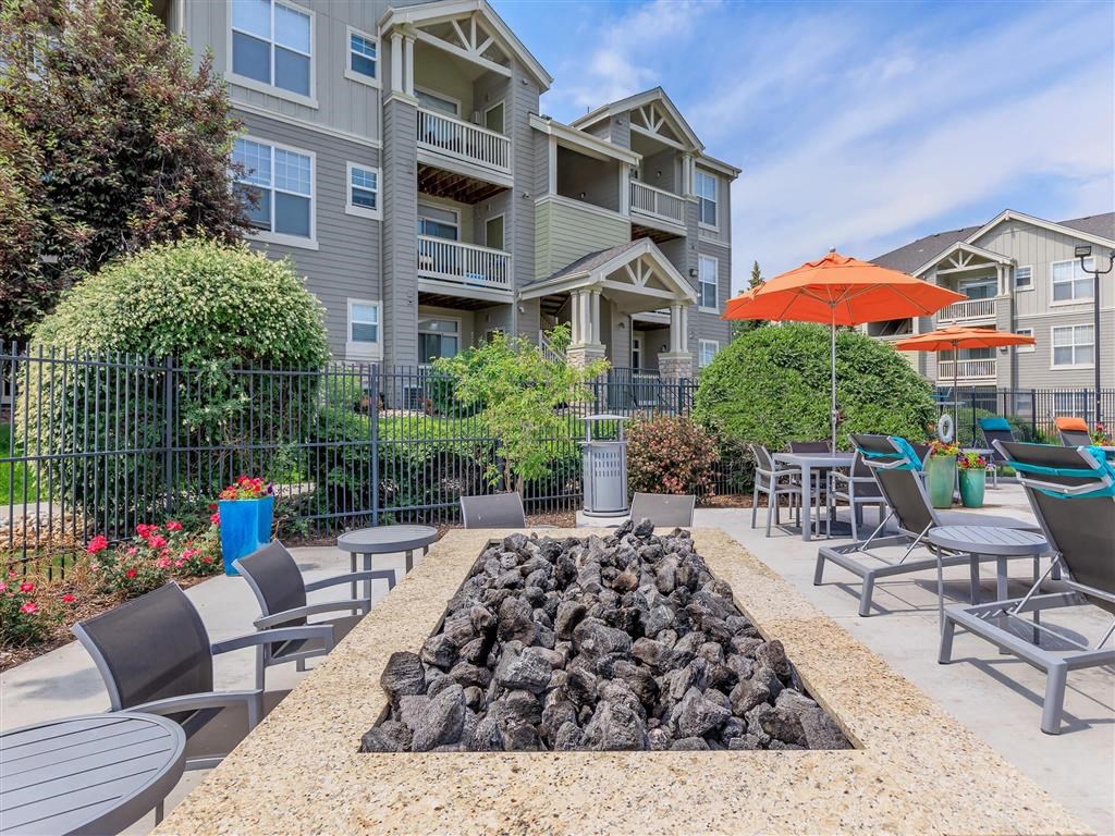 an outdoor patio with tables chairs and umbrellas and an apartment building