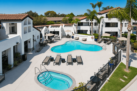 A large swimming pool surrounded by lounge chairs and umbrellas.