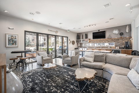 A modern living room with a black and white rug, a grey sofa, and a flat screen TV mounted on the wall.