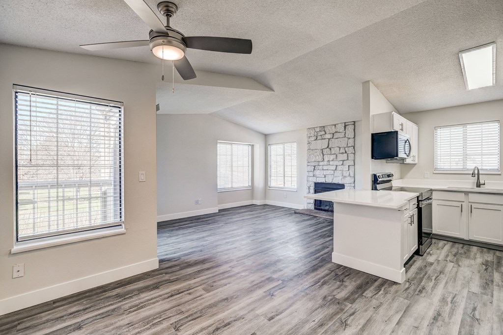 a kitchen and living room with a ceiling fan