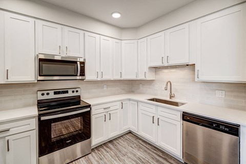 a kitchen with white cabinets and stainless steel appliances
