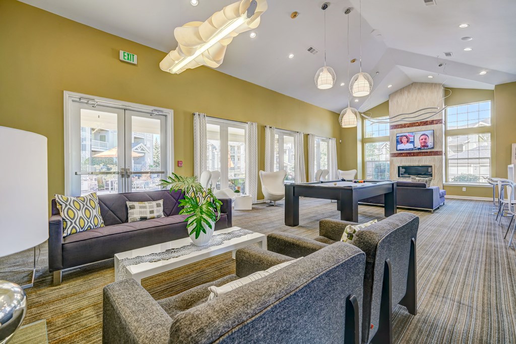a clubhouse with couches tables and a pool table