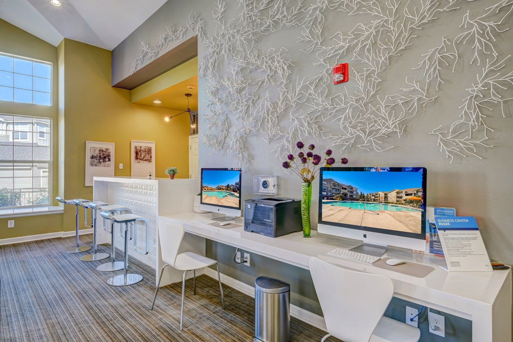 a home office with two computer monitors on a desk and a wall with a tree