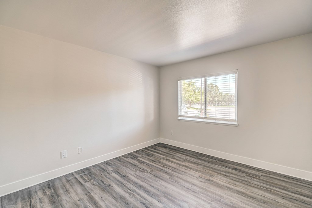 an empty room with a window and a wooden floor