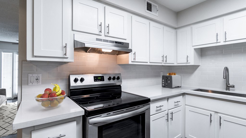 a kitchen with white cabinets and a bowl of fruit on the counter