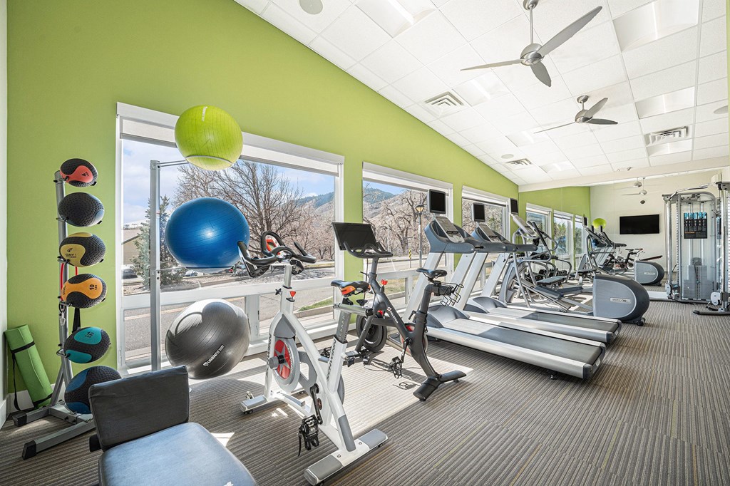 A gym with a variety of equipment including treadmills, exercise balls, and weights.