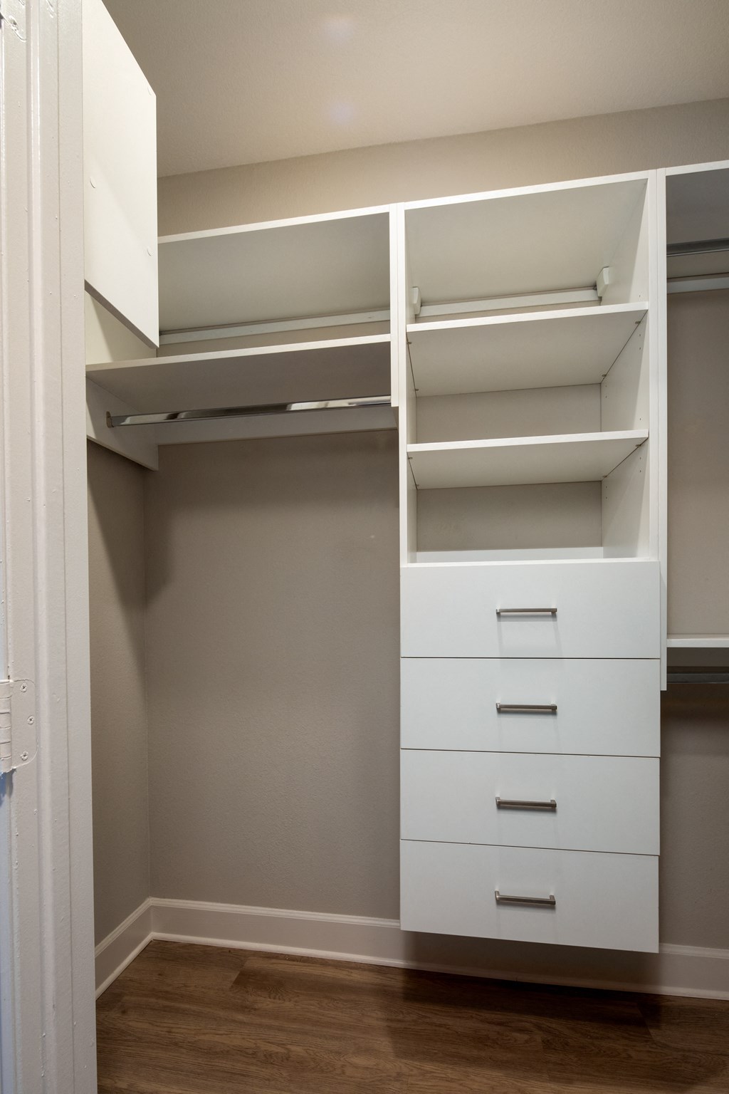 a walk in closet with white shelves and drawers and