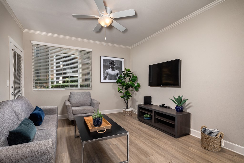 a living room with a ceiling fan and a tv