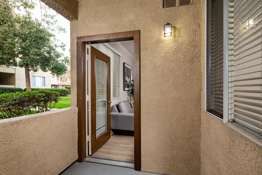 Balcony door is open to a hallway with a view of a living room