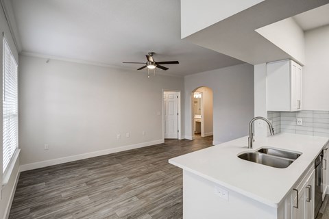 a kitchen and living room with a ceiling fan
