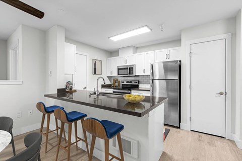 a kitchen with a large island with bar stools and a stainless steel refrigerator