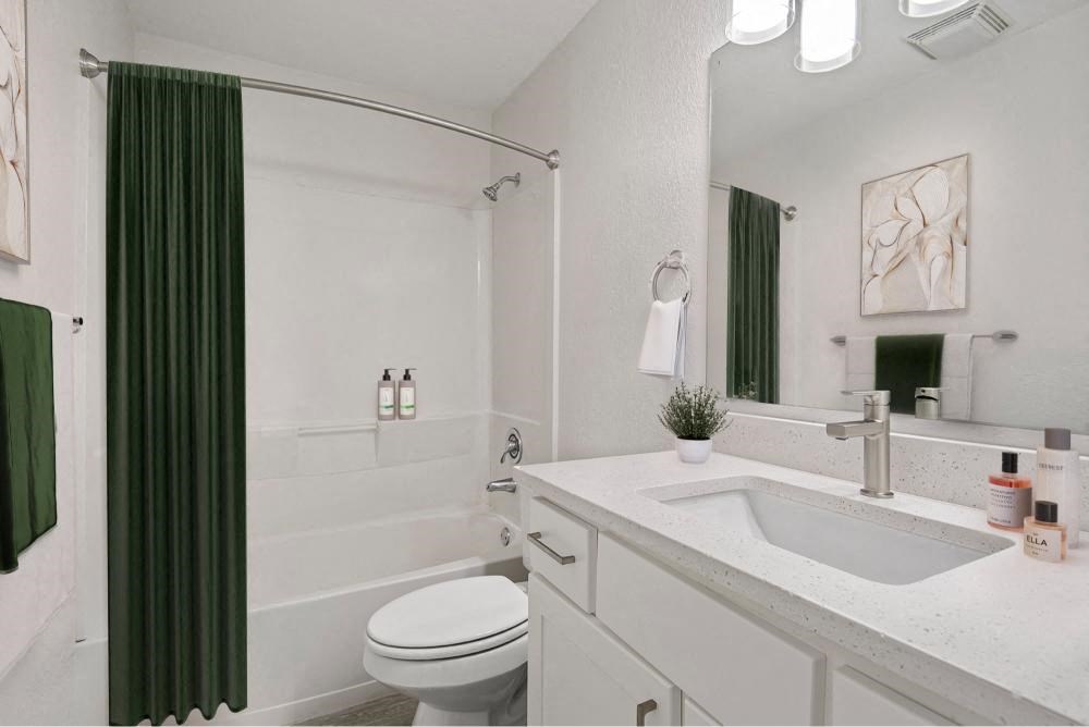 a white bathroom with a green shower curtain and a toilet and sink