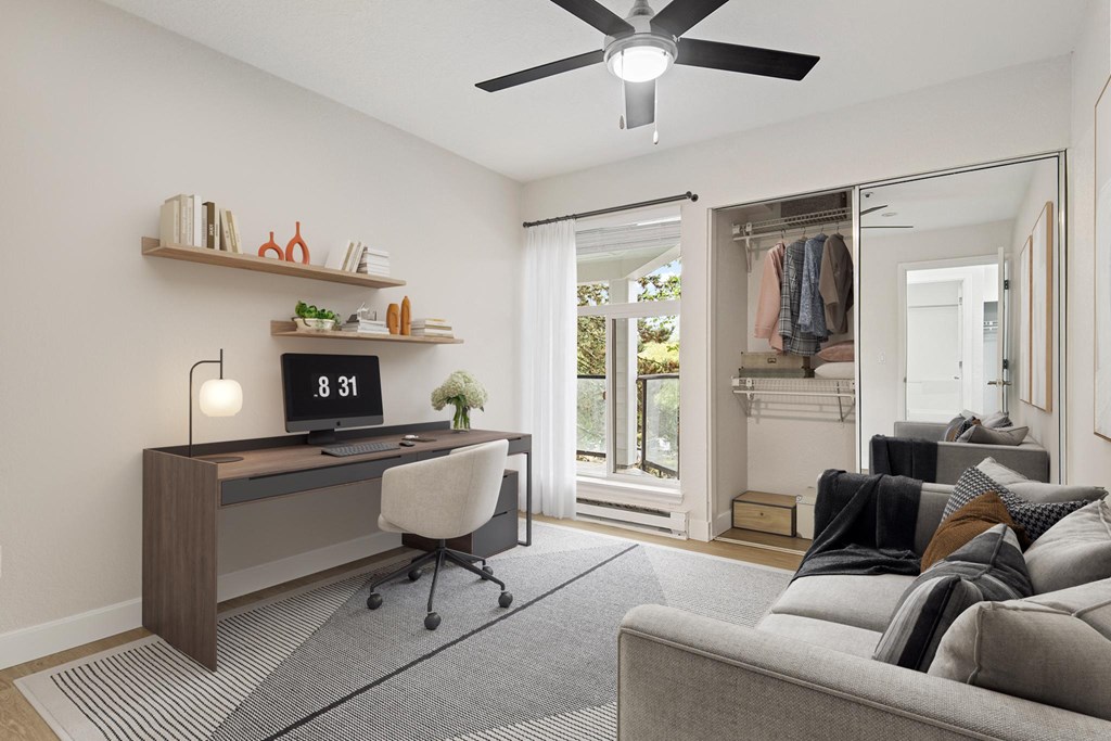 a living room with a couch and a desk and a ceiling fan