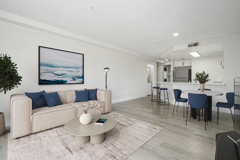 a living room with white walls and a white couch with blue pillows