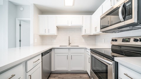 a kitchen with white cabinets and black appliances