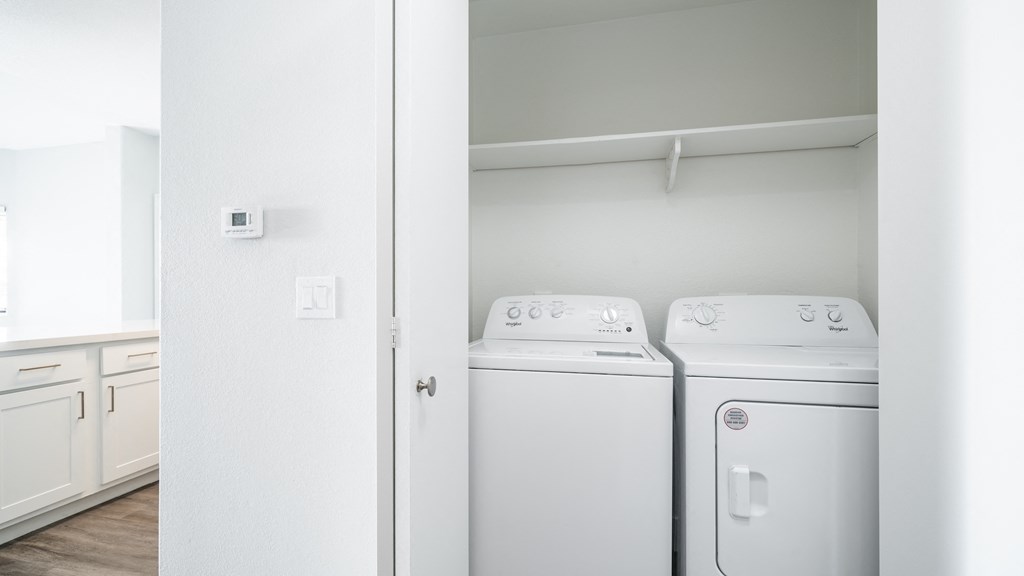 an empty laundry room with white washer and dryer machines