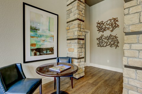 a dining area with a table and two chairs and a stone pillar with a painting on it