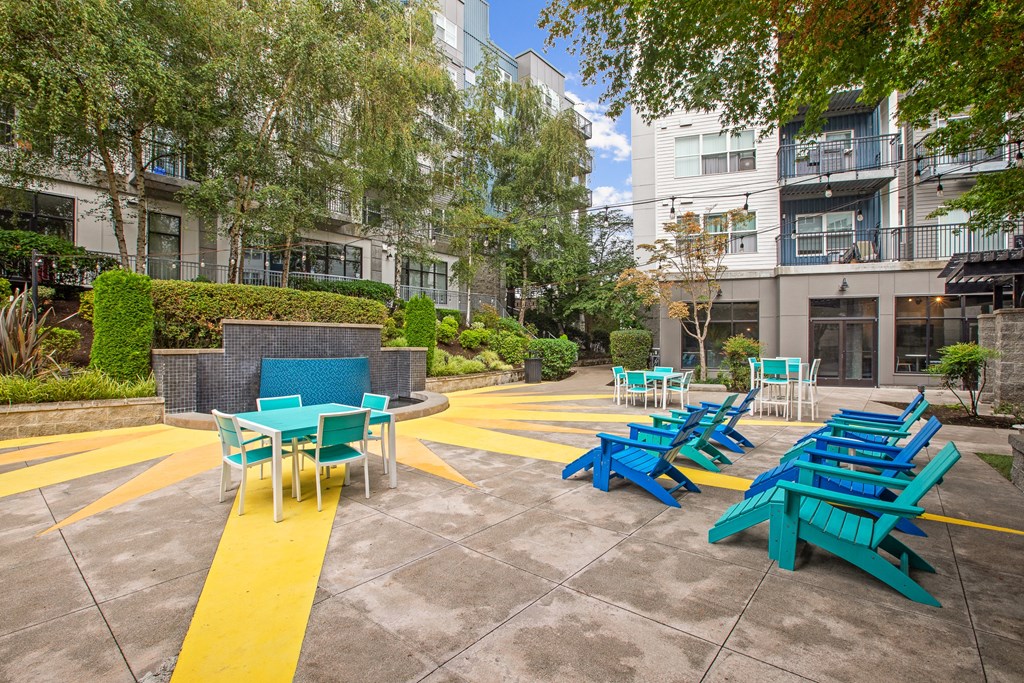 a courtyard with blue picnic tables and blue benches in front of an apartment building