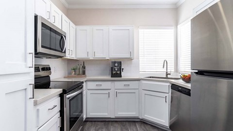 a white kitchen with stainless steel appliances and white cabinets