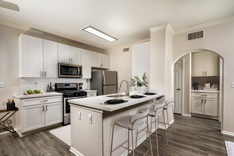 a kitchen with white cabinets and a large island with stools