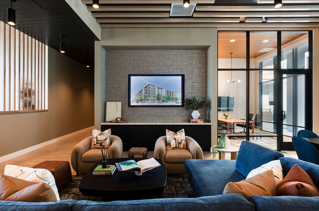 A living room with a large couch and a painting of a house on the wall.