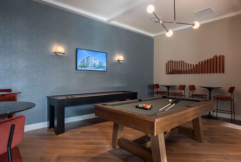 A room with a pool table and a television mounted on the wall.