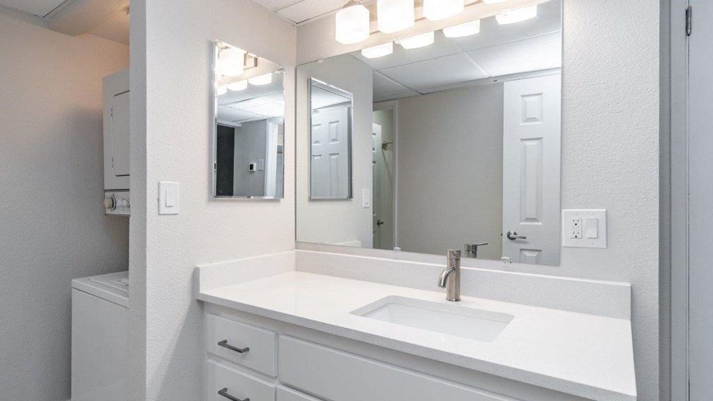 A white bathroom vanity with a sink and mirror.