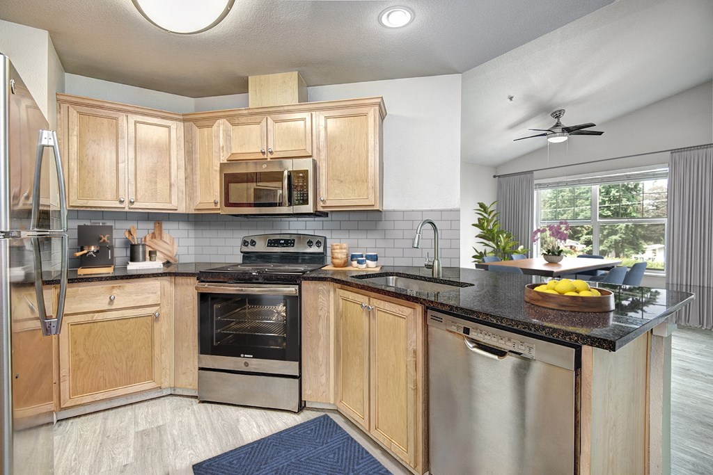a kitchen with wooden cabinets and a black counter top