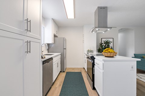 a kitchen with white cabinets and stainless steel appliances and a counter top with a basket