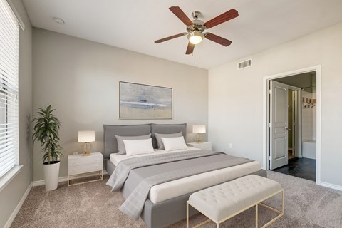 Bedroom with grey bed set, ceiling fan and bright window.
