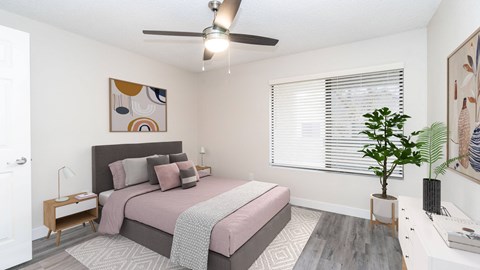 a bedroom with a large window and a ceiling fan