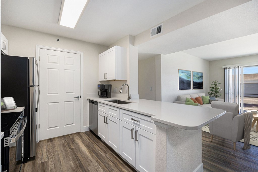 A kitchen with white cabinets and a black refrigerator.