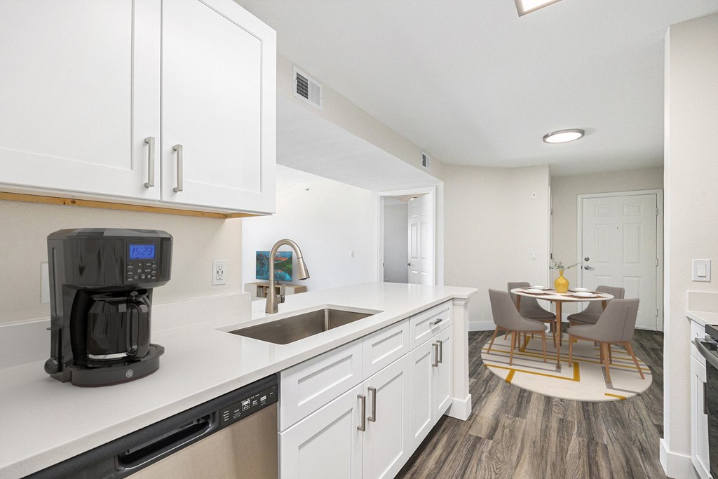 A kitchen with white cabinets and a black coffee maker.